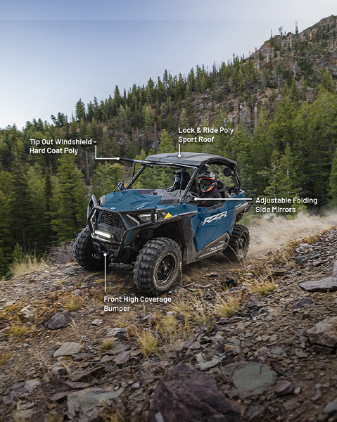 Tip-out hard coat poly windshield, Lock & Ride poly sport roof, adjustable folding side mirrors, and front high coverage bumper accessories from the Explorer Package installed on a 2025 Polaris RZR Trail side-by-side.