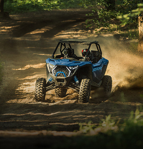2 riders cruising a trail in a high-performance 2026 Polaris RZR SxS.