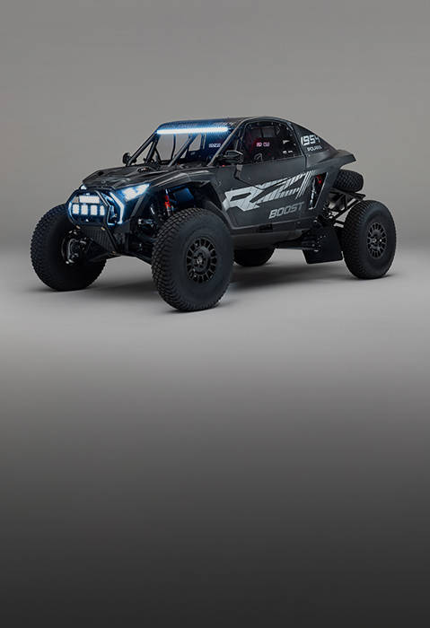 Black 2027 Polaris RZR Pro R Factory Boost SxS with LED lights and spare tire displayed in a studio.