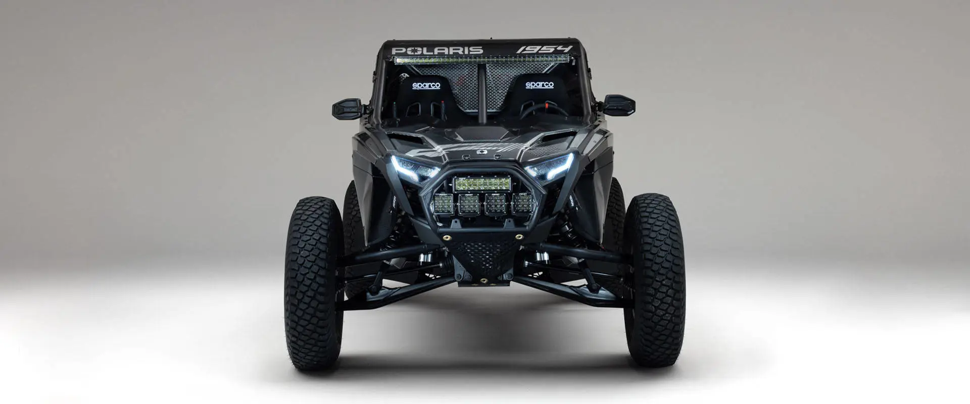 Front view of a 2027 Polaris RZR Pro R Factory Boost SxS with LED headlights, auxiliary lights and Sparco racing seats.