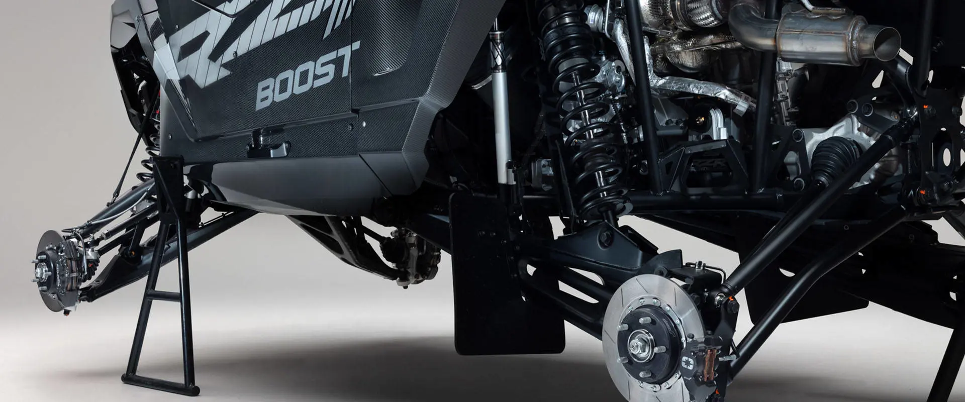 Close-up of the front and rear suspension, brake assemblies and powertrain on a 2027 Polaris RZR Pro R Factory Boost SxS.