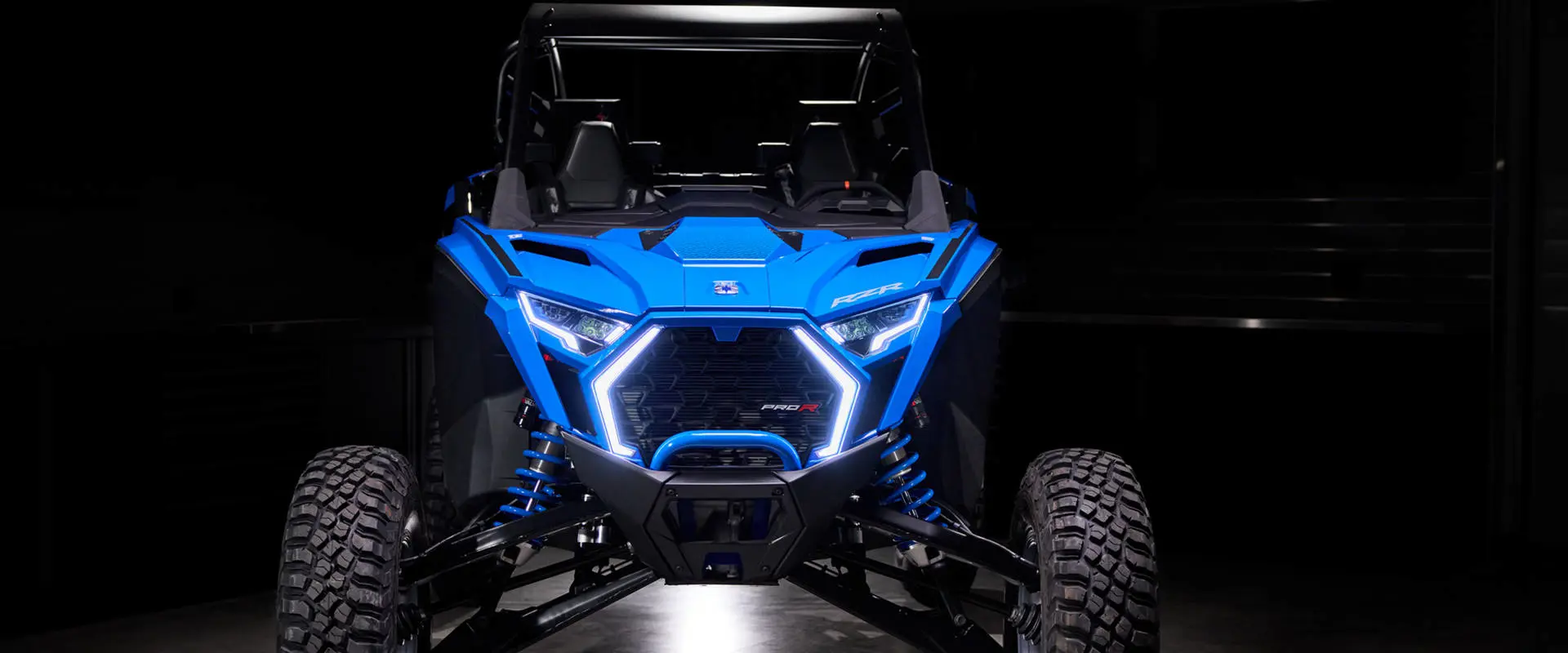 Front view showing the glowing C-shaped LED headlights and aggressive grille of the RZR Pro R Ultra Edition Velocity Blue.