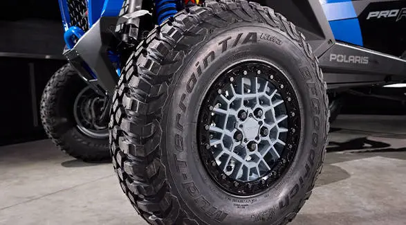 Close-up detail of a BFGoodrich Mud-Terrain T/A KM3 tire and custom wheel on the RZR Pro R Ultra Edition Velocity Blue SxS.
