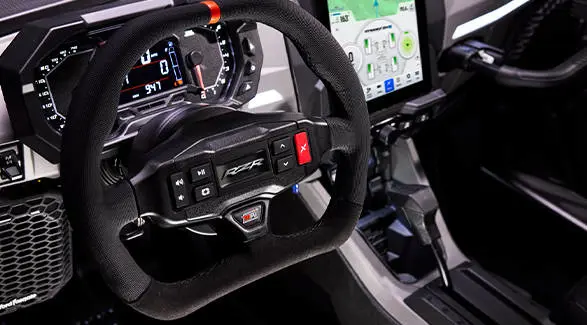 Cockpit detail showing the RZR-branded steering wheel and digital instrument cluster.