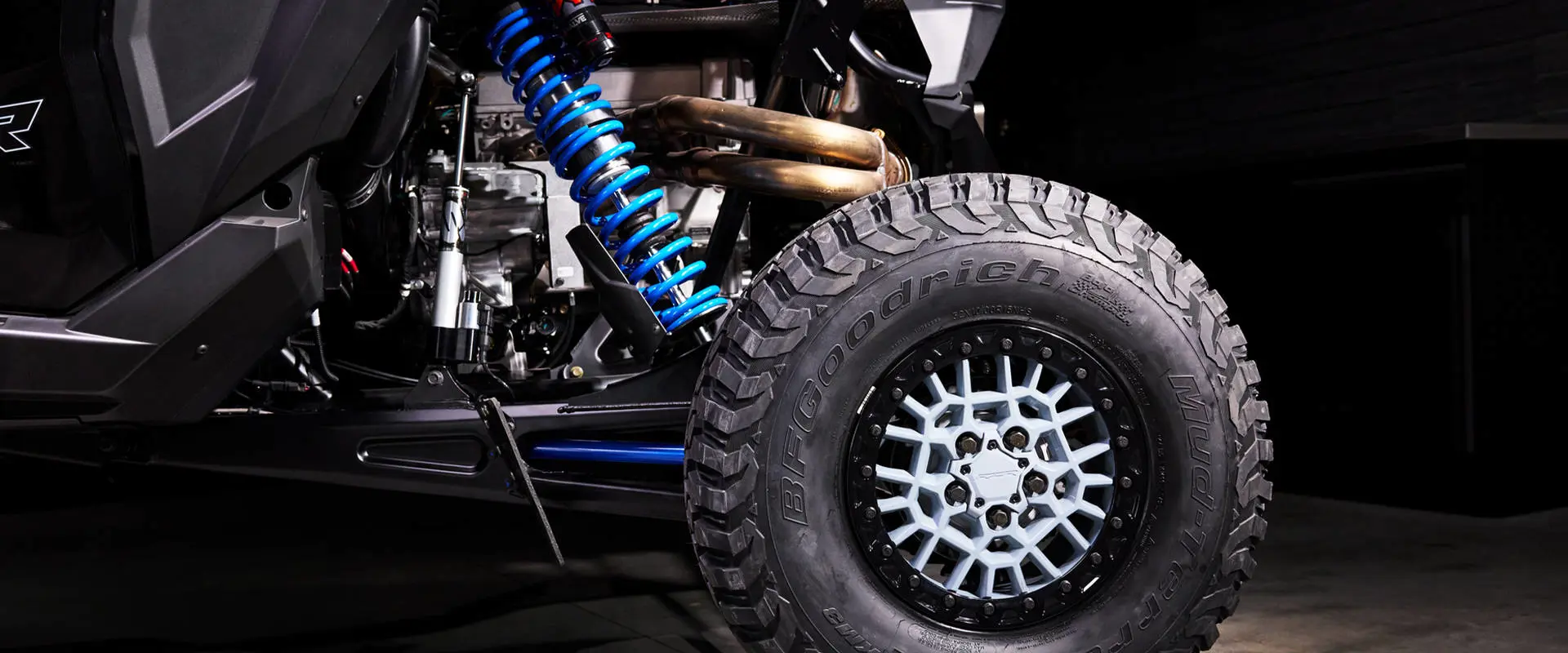 Suspension detail shot of the bright blue rear coil spring and FOX shock absorber on the RZR Pro R Ultra Edition.