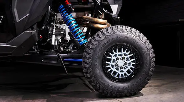 Suspension detail shot of the bright blue rear coil spring and FOX shock absorber on the RZR Pro R Ultra Edition.