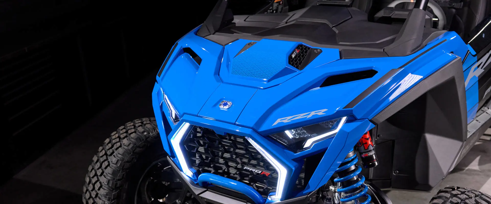 High-angle hood shot focusing on the Polaris logo and bright white LED lights on the front grille.