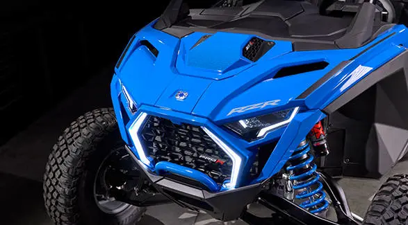 High-angle hood shot focusing on the Polaris logo and bright white LED lights on the front grille.