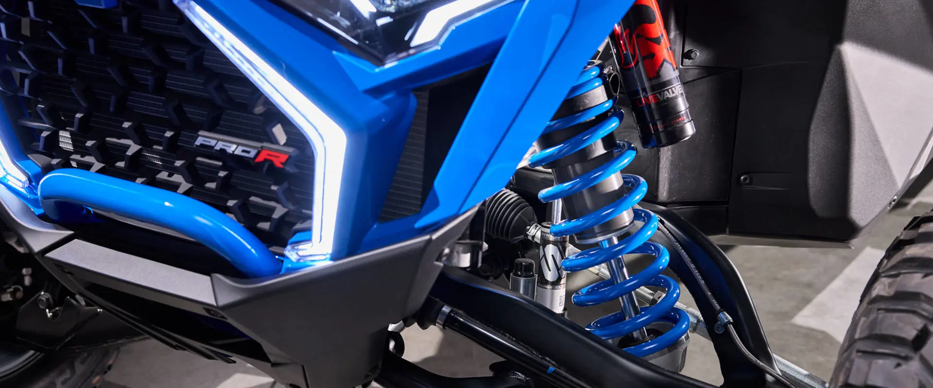 Front suspension detail highlighting the bright blue coil and FOX shock assembly.