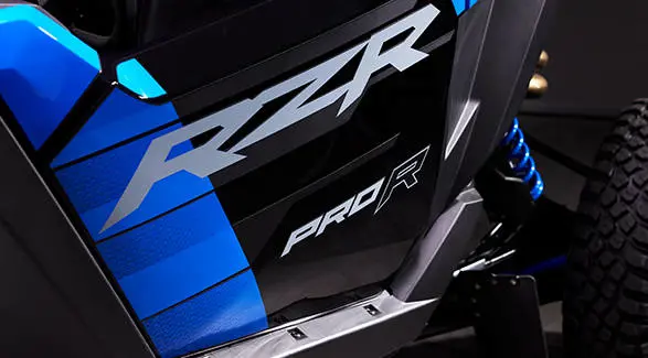Body panel close-up of the RZR PRO R logo and grey graphics on the Velocity Blue side panel.