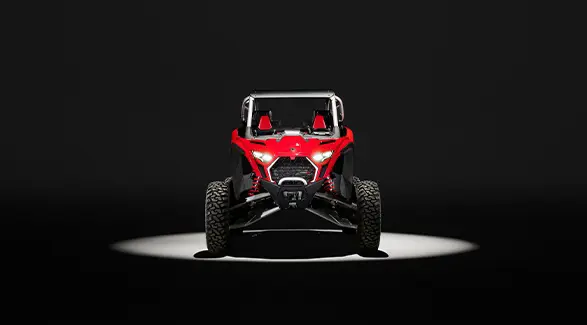 Front end view of a Indy Red 2026 Polaris RZR Pro R SxS in the spotlight in a dark room.