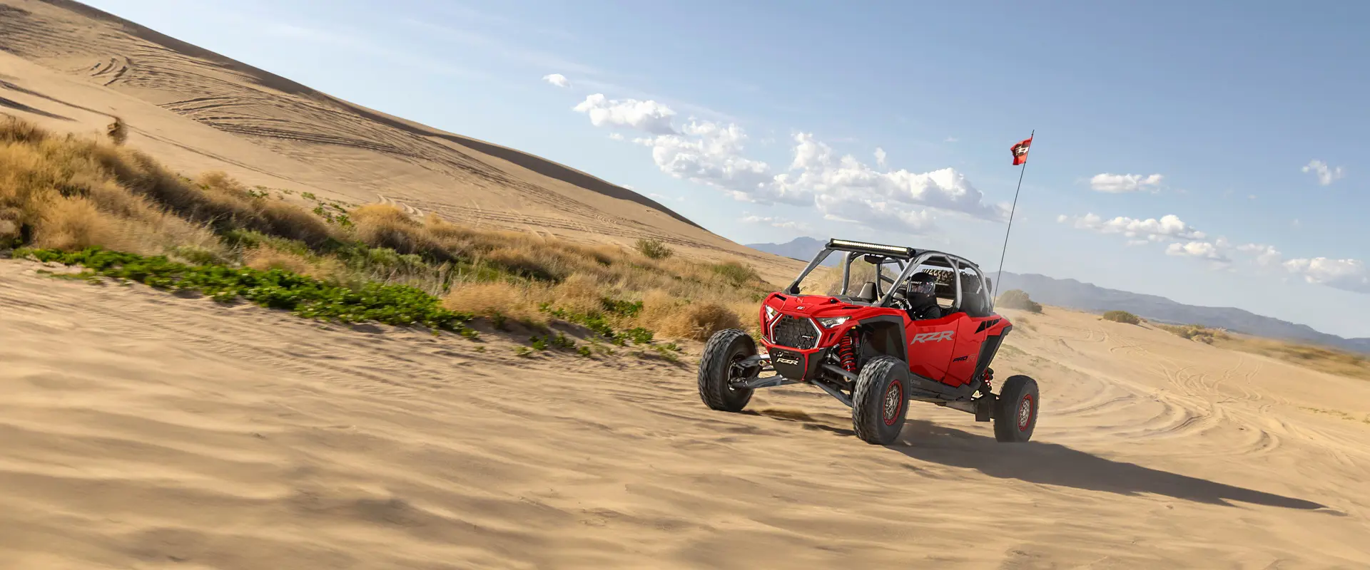 A 2026 Polaris RZR Pro R side-by-sides cruising through the desert on a sunny day.