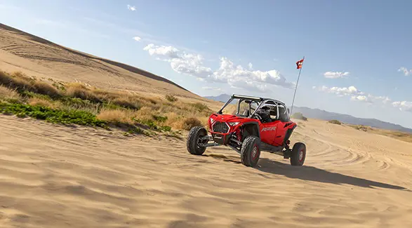 A 2026 Polaris RZR Pro R side-by-sides cruising through the desert on a sunny day.