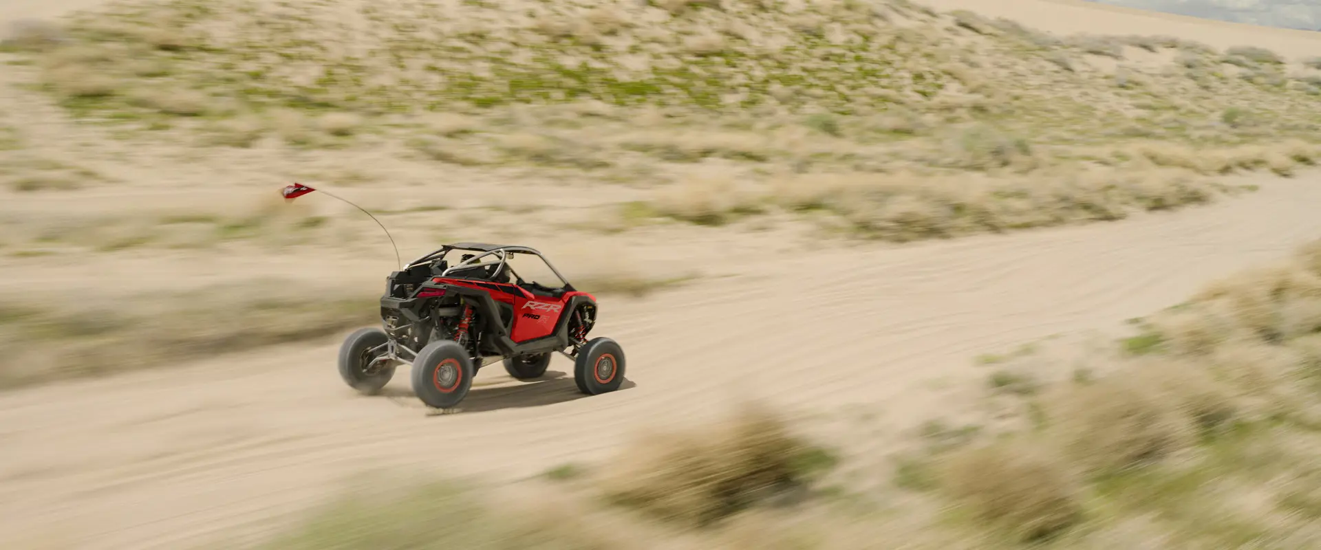 Long-range view of a 2026 Polaris RZR Pro R SxS cruising through the desert.