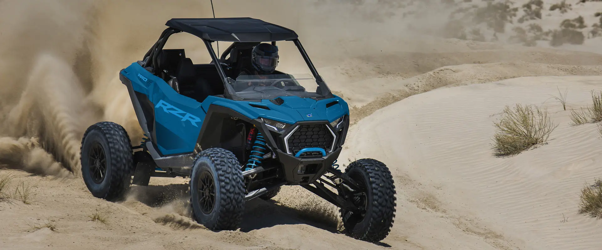 Un Side-by-Side Polaris RZR Pro S Ultimate de 2026 en color Earth Blue arrojando arena en el desierto.