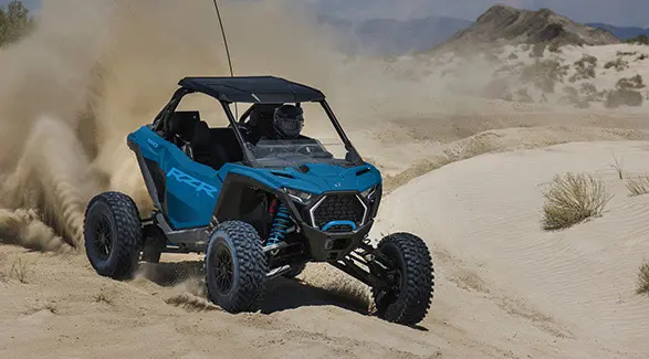 A 2026 Polaris RZR Pro S Ultimate SxS in Earth Blue throwing sand in the desert.
