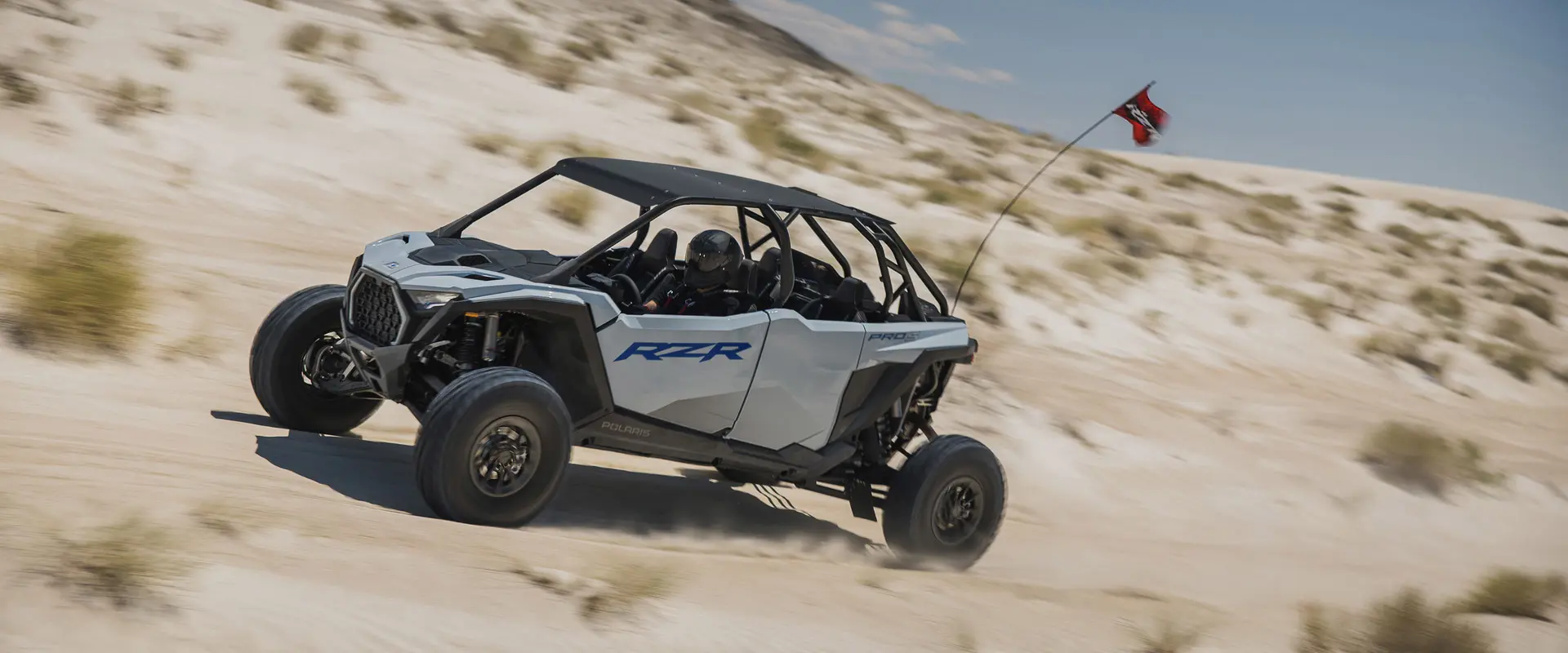 Perfil lateral de un Side-by-Side Polaris RZR Pro S 4 Sport de 2026 en Storm Gray recorriendo las dunas.