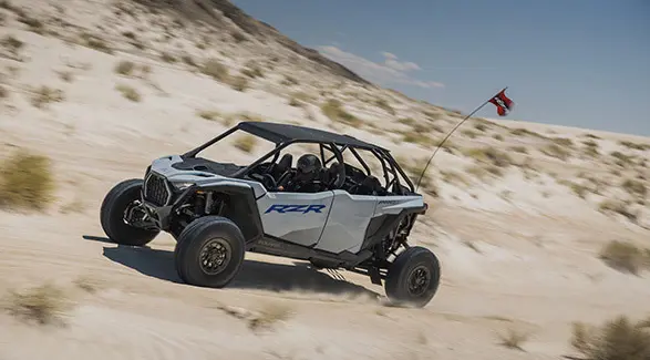 Side profile of a 2026 Polaris RZR Pro S 4 Sport SxS in Storm Gray cruising in the dunes.