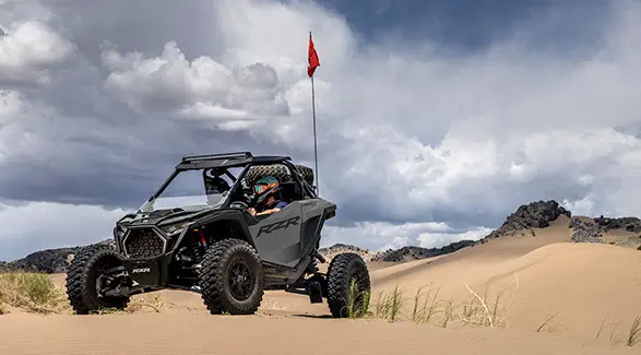 2 helmeted riders in a 2026 Polaris RZR Pro S Ultimate SxS ready to ride.