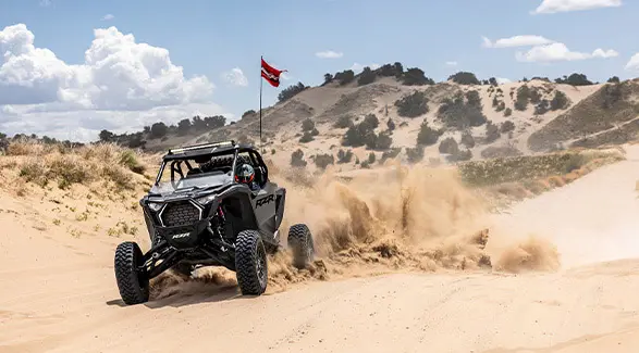 RZR Pro Front view of a 2026 Polaris RZR Pro S Ultimate SxS in Slate Gray speeding across a desert terrain.