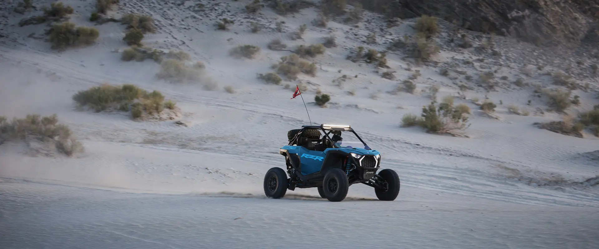 Perfil lateral de un Side-by-Side Polaris RZR Pro S Ultimate de 2026 en Earth Blue avanzando en el desierto.