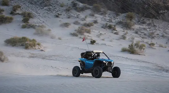Perfil lateral de un Side-by-Side Polaris RZR Pro S Ultimate de 2026 en Earth Blue avanzando en el desierto.