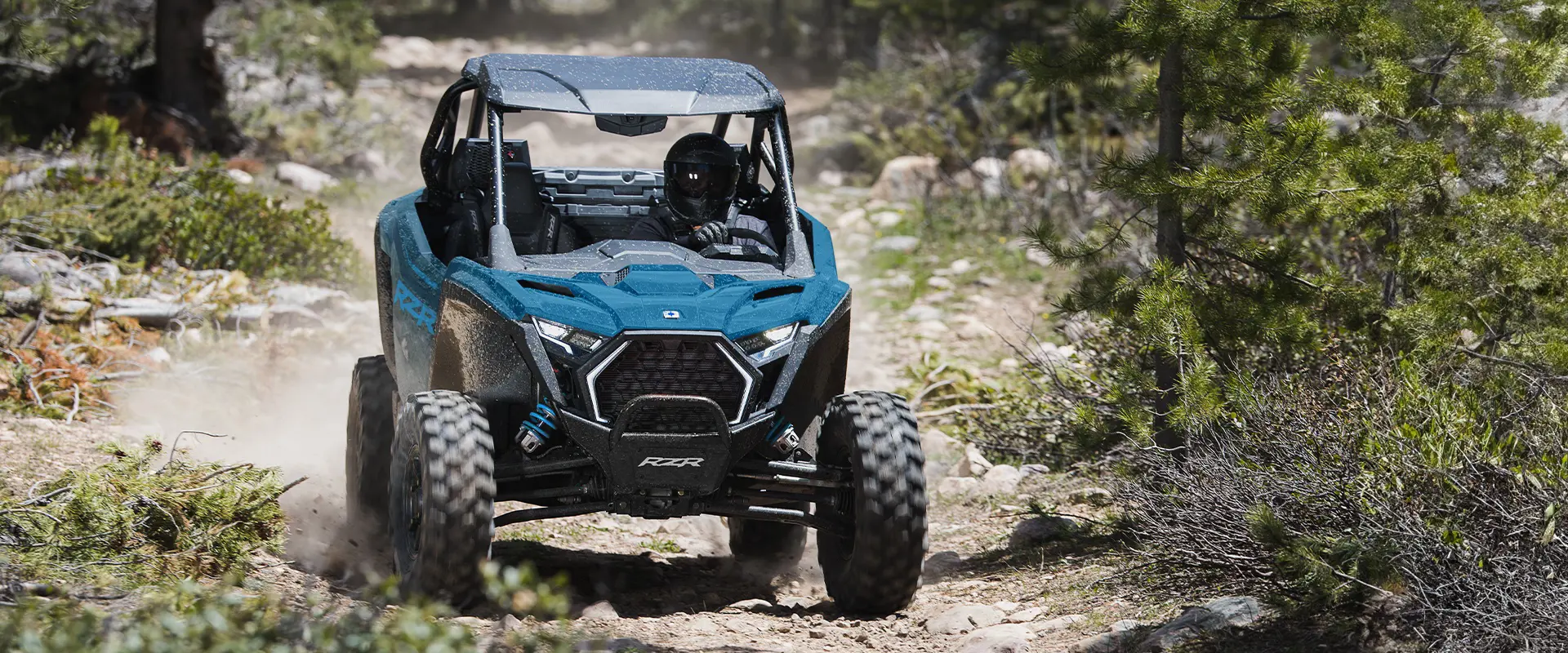 Vista de la parte delantera de un Side-by-Side Polaris RZR Pro XP de 2026 en un bosque.