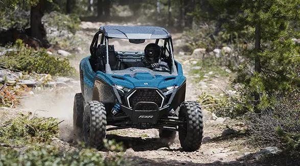 Vista de la parte delantera de un Side-by-Side Polaris RZR Pro XP de 2026 en un bosque.