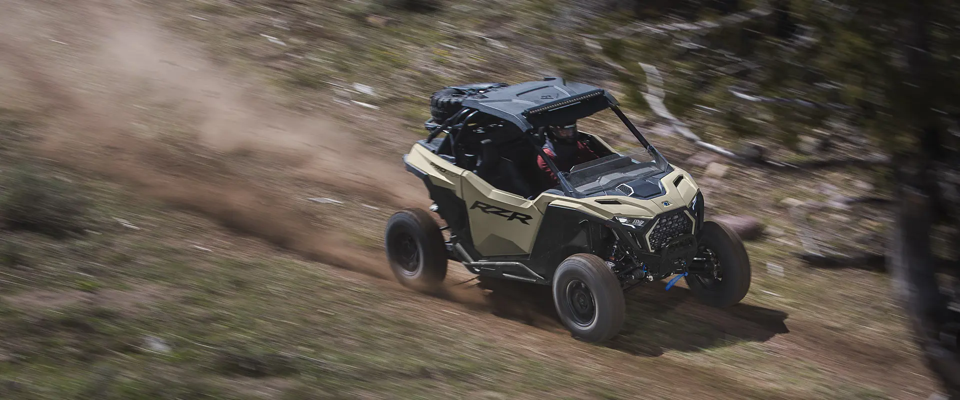 Vista lateral aérea de un Side-by-Side Polaris RZR Pro XP de 2026 a toda velocidad por un sendero.
