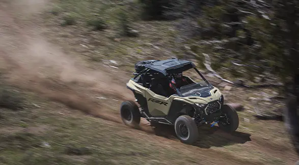 Vista lateral aérea de un Side-by-Side Polaris RZR Pro XP de 2026 a toda velocidad por un sendero.