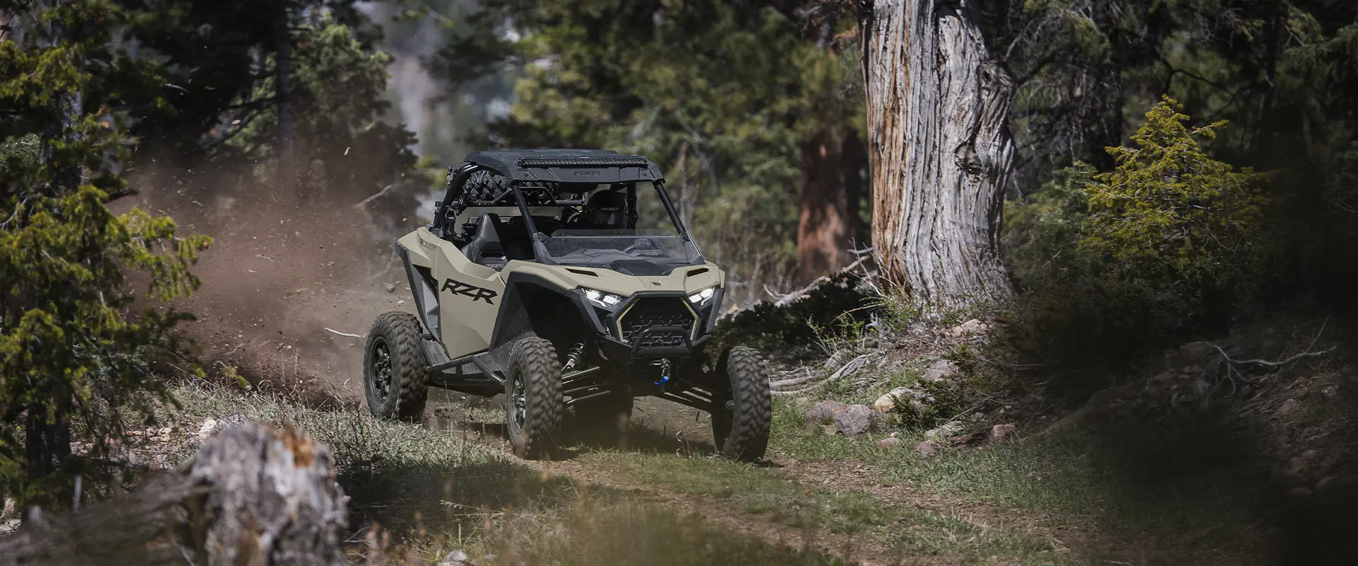 Un Side-by-Side Polaris RZR Pro XP de 2026 arrojando tierra un sendero en el bosque.