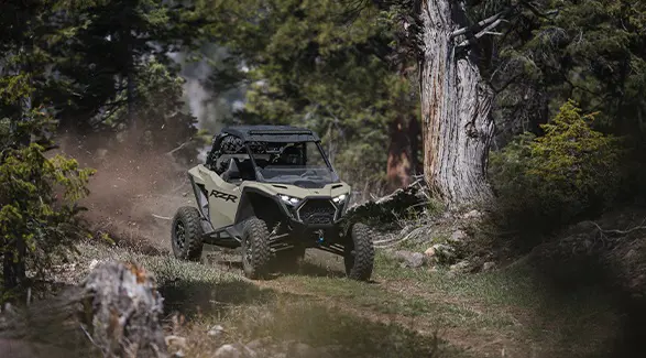 A 2026 Polaris RZR Pro XP SxS throwing dirt down a forest trail.
