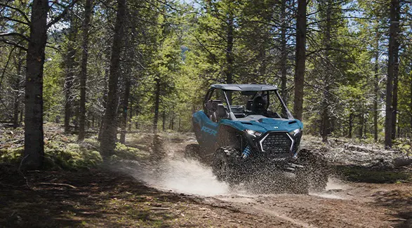 A 2026 Polaris RZR Pro XP SxS conquering a mud pit in a forest with ease.