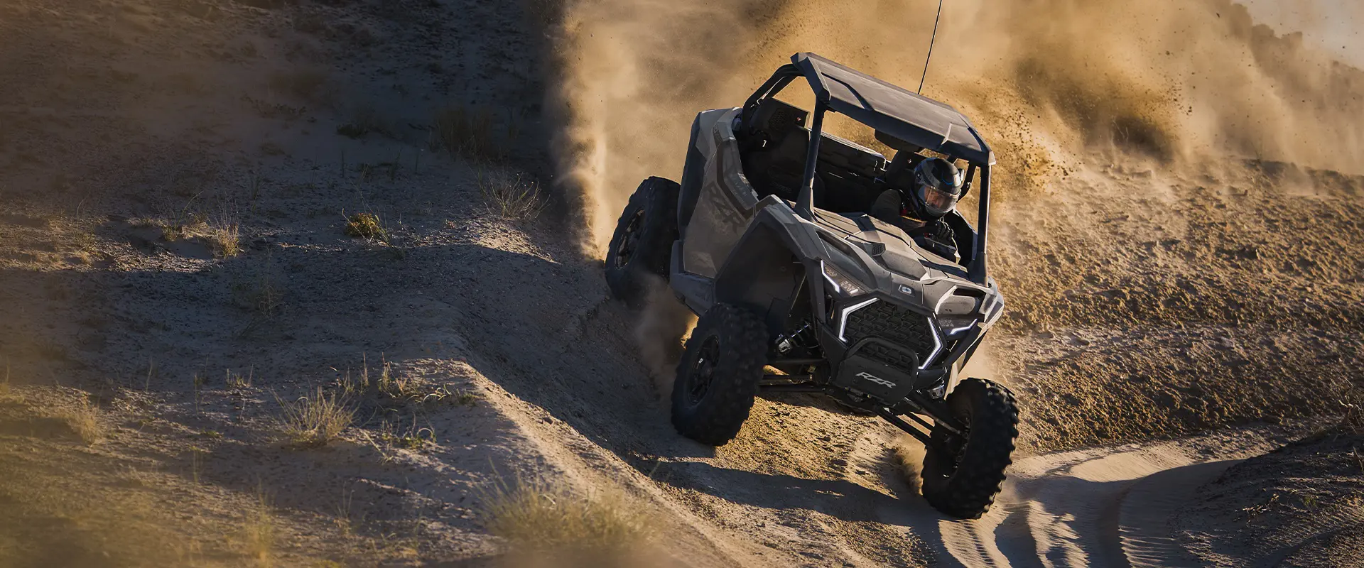 Aerial view of a 2026 Polaris RZR Pro XP side-by-side throwing sand in the dunes.