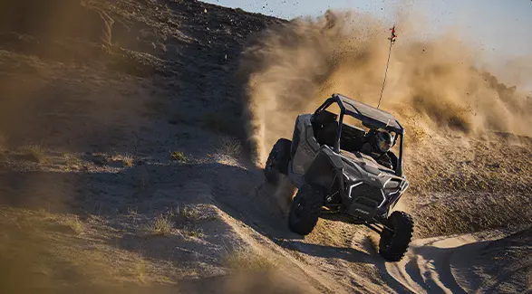 Aerial view of a 2026 Polaris RZR Pro XP side-by-side throwing sand in the dunes.