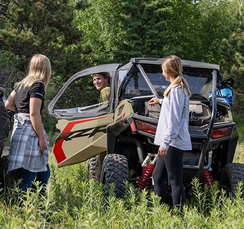 A boy showcasing the Rockford Fosgate Audio system in his 2026 Polaris RZR Trail S side by side to 2 girls.
