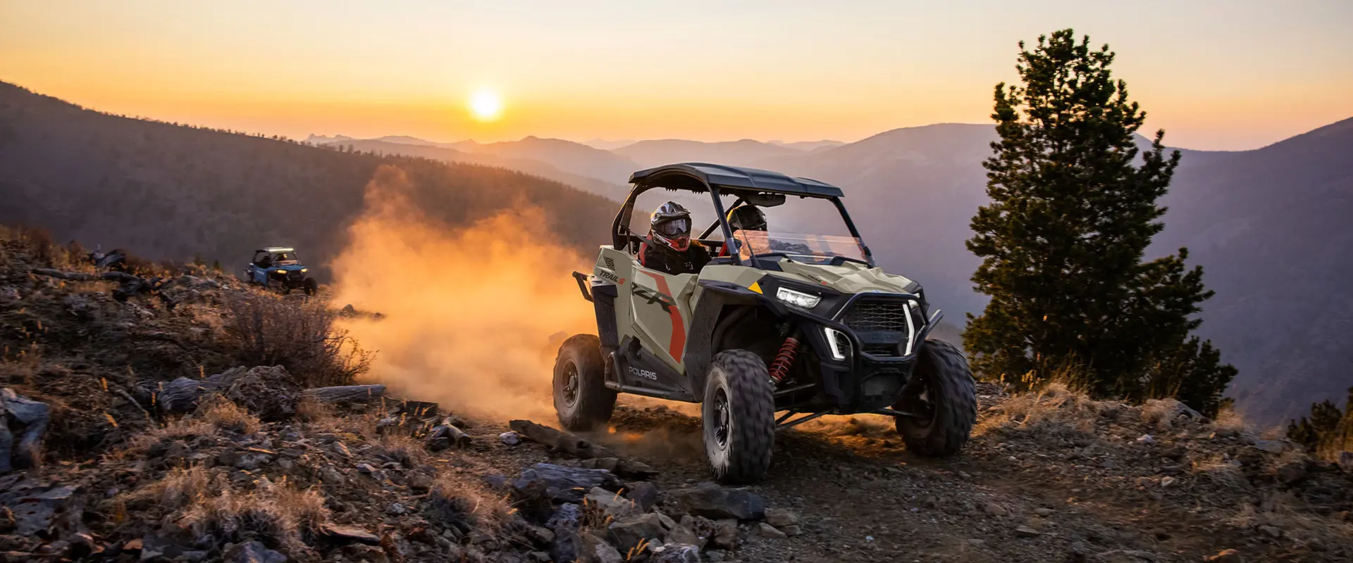 A 2026 Polaris RZR Trail S side by side cruising over rocky terrain at dusk.