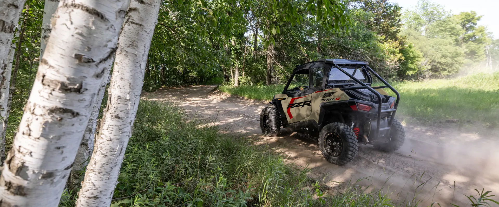 Rear/side view of a 2026 Polaris RZR Trail S side by side on a trail.