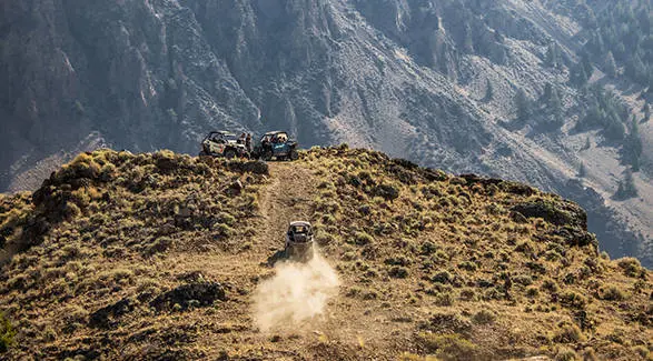 A 2026 Polaris RZR Trail side-by-side climbing a hill to meet two other RZR Trail side by sides.