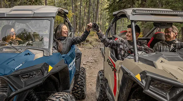 People pounding knuckles while seated comfortably in their 2026 Polaris RZR Trail side-by-sides.