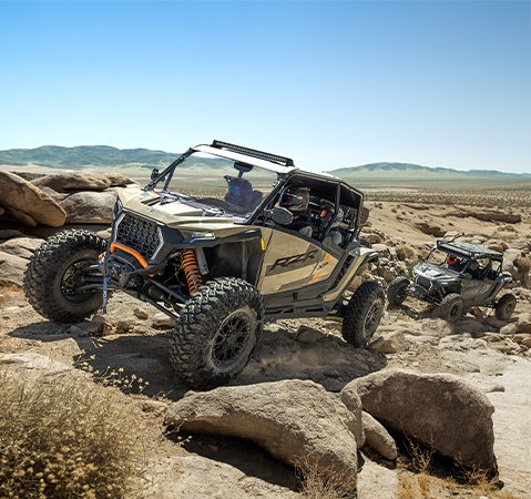 Two 2026 Polaris RZR XP S 4 side-by-sides crawling over rocky terrain with 32-inch tires.