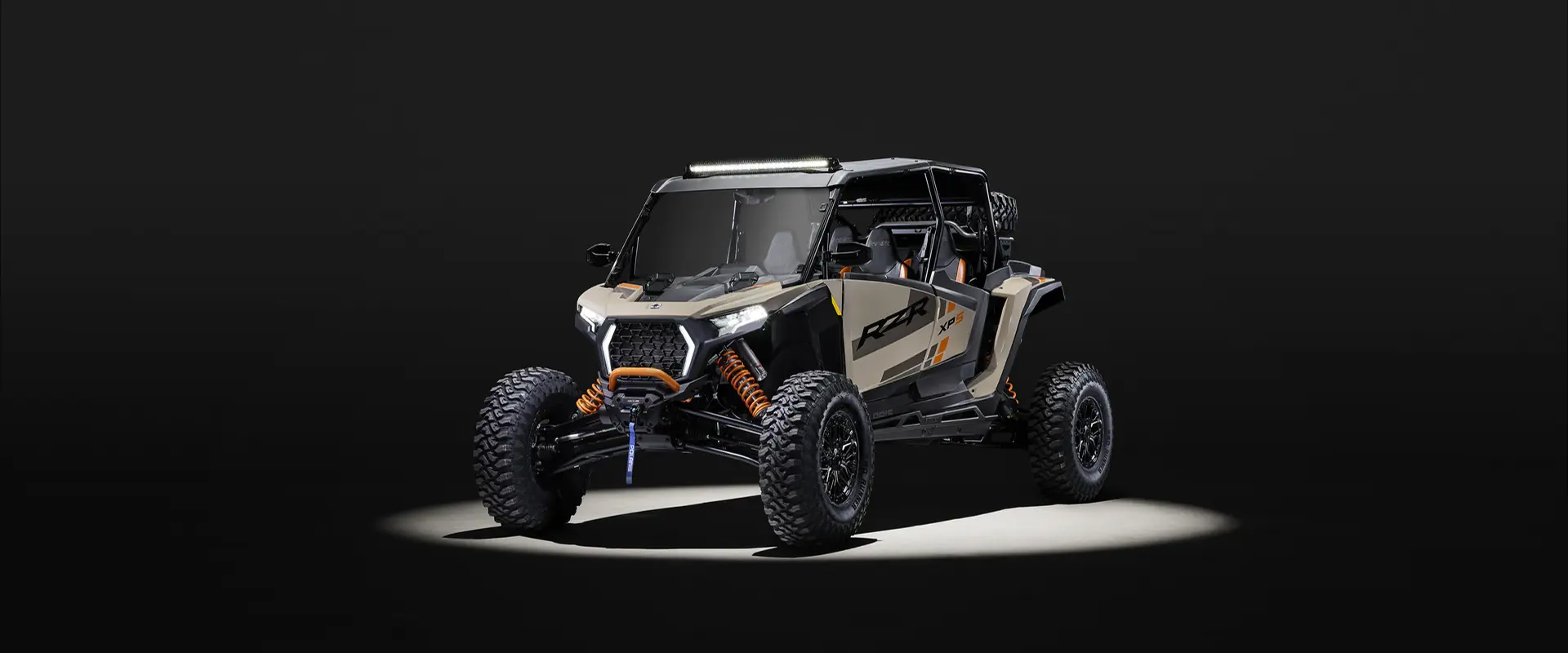 Front end view of a 2026 Polaris RZR XP S 4 SxS with spotlight on it in a dark room.