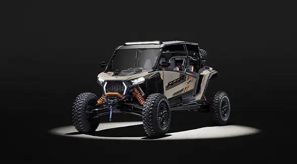 Front end view of a 2026 Polaris RZR XP S 4 SxS with spotlight on it in a dark room.