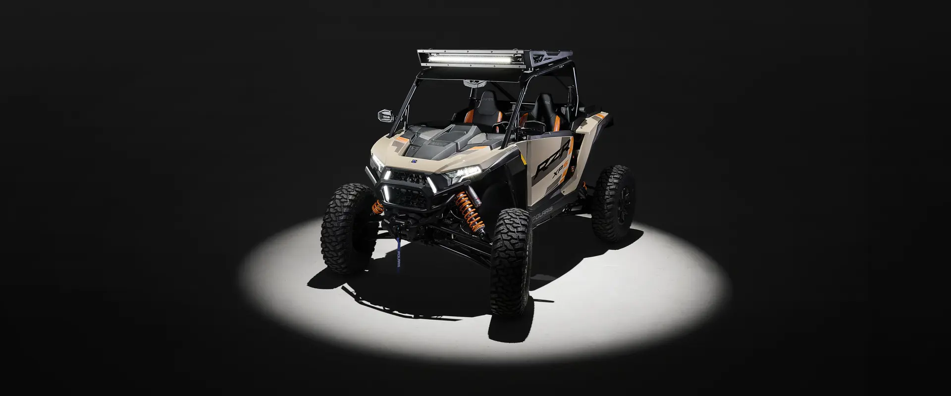 Aerial view of a 2026 Polaris RZR XP S 4 SxS entrenched in spotlight in a dark room.