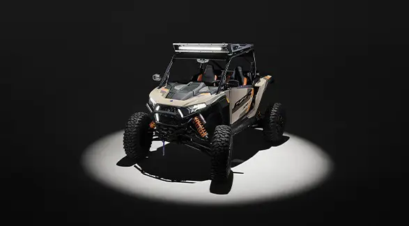 Aerial view of a 2026 Polaris RZR XP S 4 SxS entrenched in spotlight in a dark room.