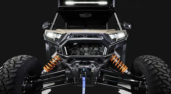 Front end view of a 2026 Polaris RZR XP S 4 SxS entrenched in spotlight in a dark room.
