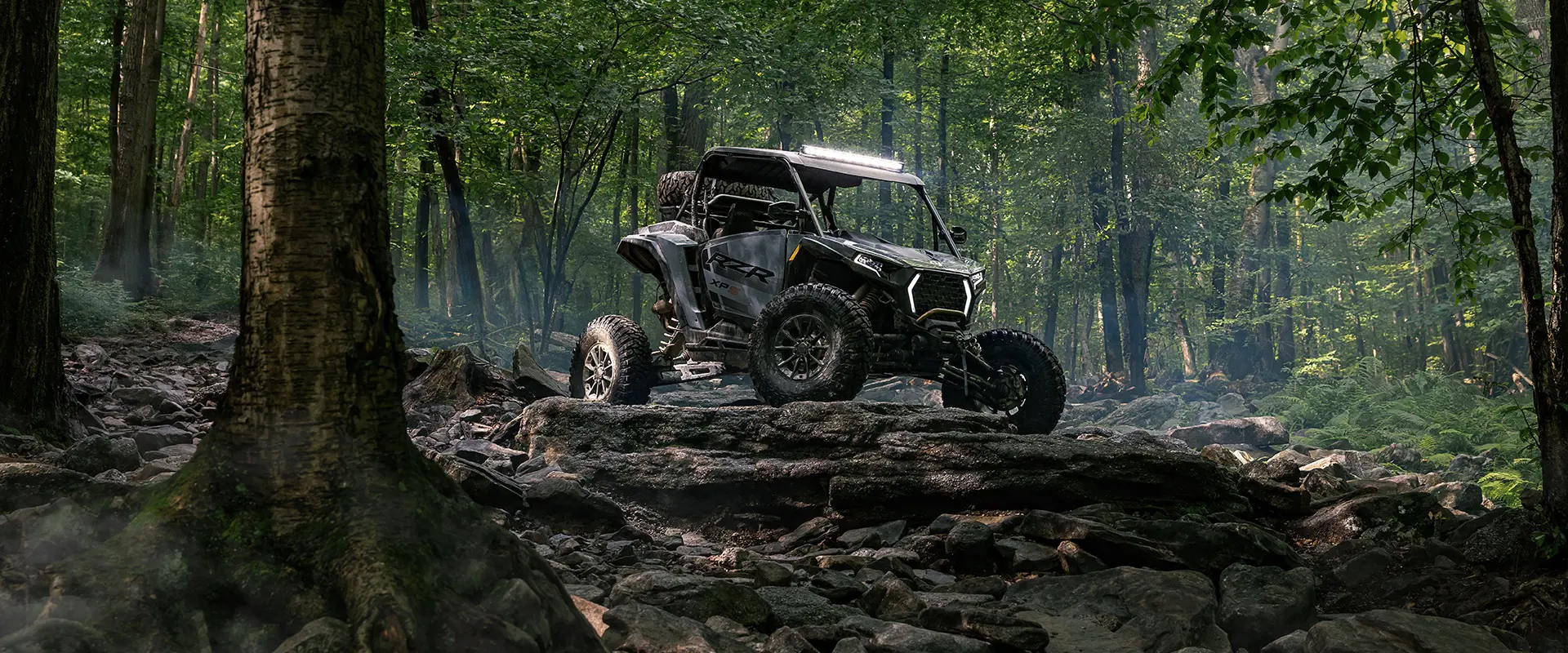 A 2026 Polaris RZR XP S side-by-side parked on a rocky hill in the forest.