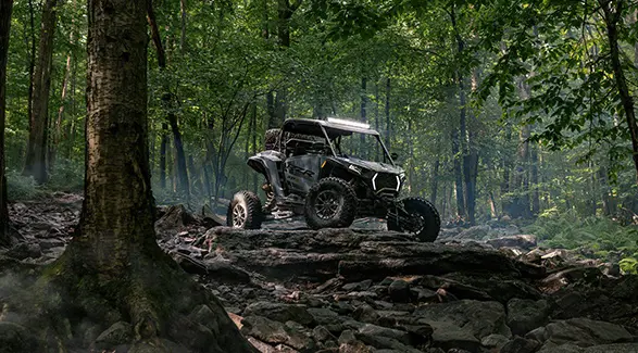 A 2026 Polaris RZR XP S side-by-side parked on a rocky hill in the forest.