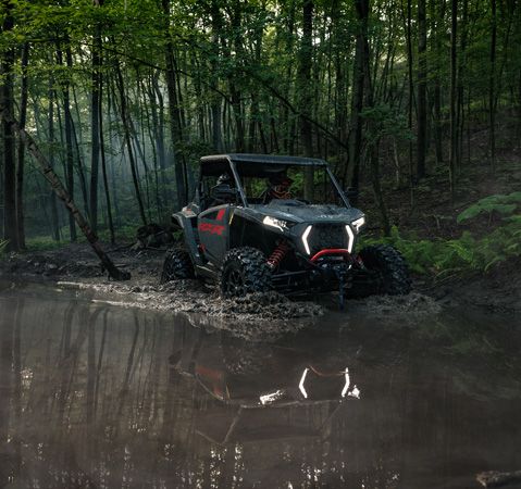 A 2026 Polaris RZR XP Ultimate side-by-side powering through a mudhole with ease.