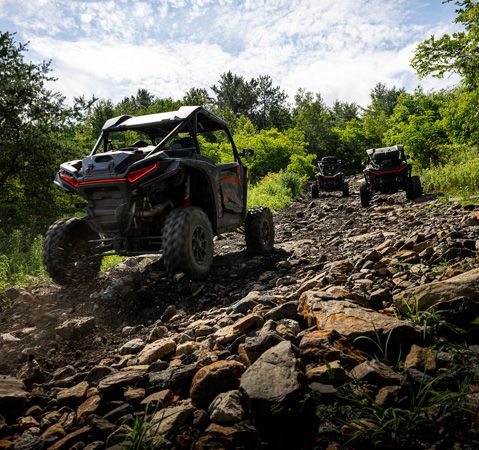 3 2026 Polaris RZR XP Ultimate side-by-sides driving over rough terrain with ease.